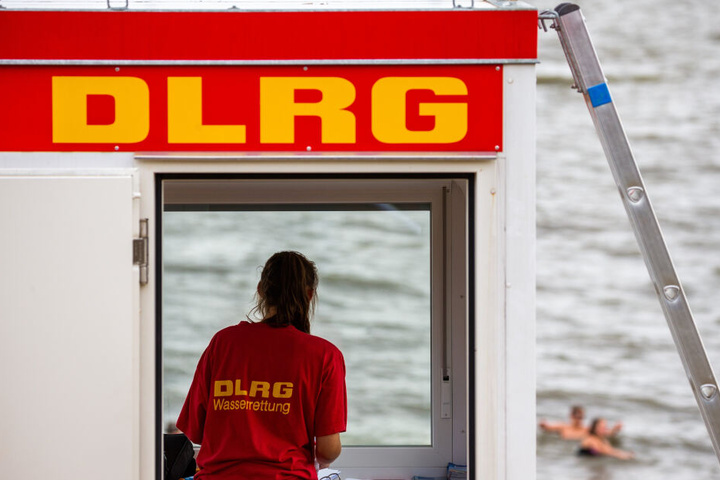 Eine Rettungsschwimmerin der DLRG (Deutsche Lebens-Rettungs-Gesellschaft) steht vor dem Fenster eines Wachturms.