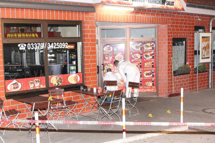 Polizisten markierten die Einschusslöcher in der mit Werbung beklebten Tür.