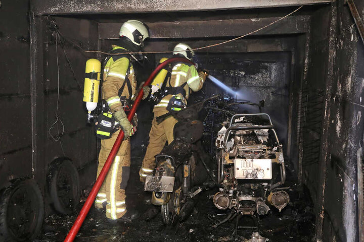 Zwei Kameraden der Feuerwehr löschen den Brand eines Motorrades.