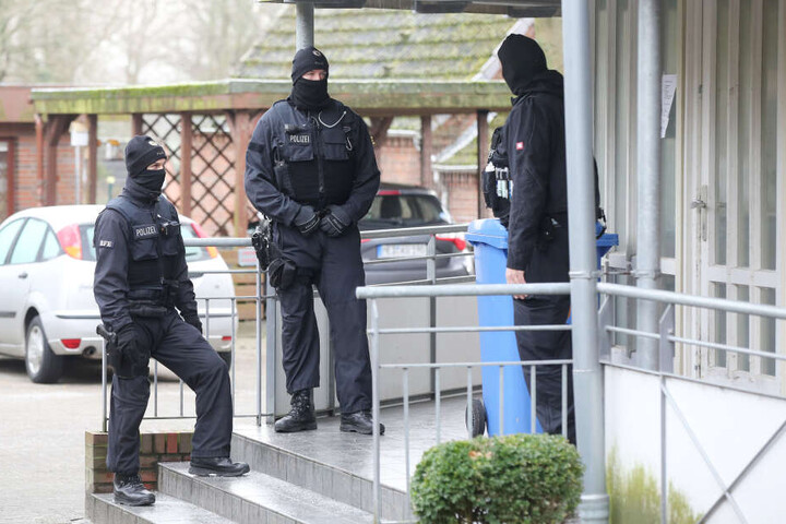 Einsatzkräfte der Polizei stehen während einer Durchsuchung vor einem Haus im Kreis Dithmarschen.