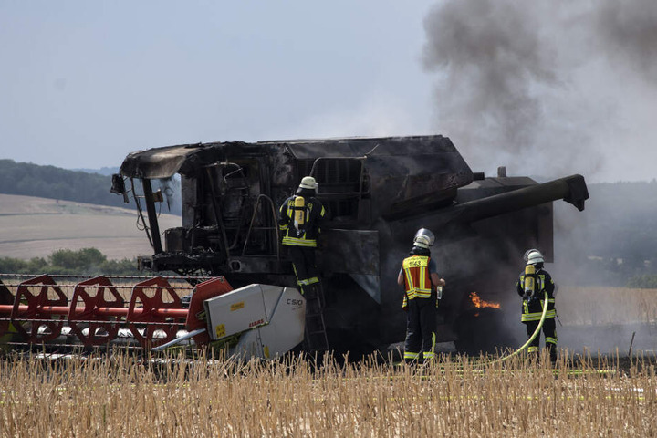 Feuerwehrleute löschen die letzten Flammen am Mähdrescher.