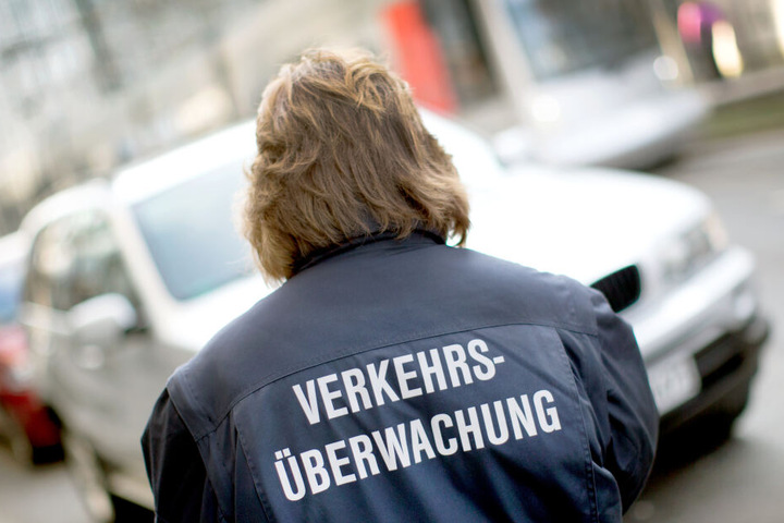 Eine Mitarbeiterin des Ordnungsamtes kontrolliert parkende Autos.