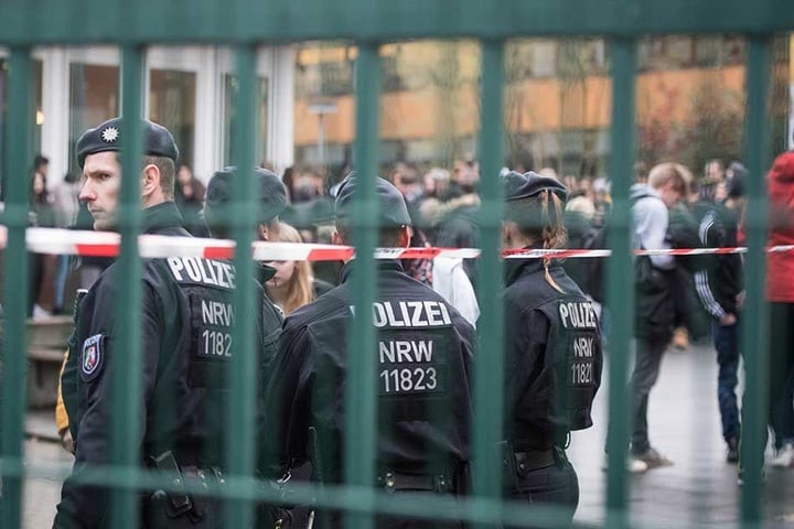 Polizisten stehen im Schulgelände, die Schüler haben das Gebäude verlassen.