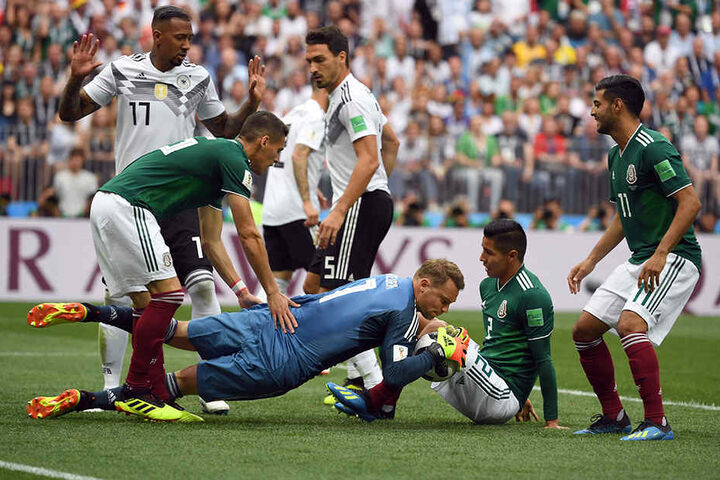Manuel Neuer (MItte) begräbt die Kunstlederkugel nach einer Ecke unter sich.