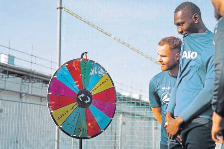 Tobias Müller und Tarsis Bonga (r.) blicken gespannt auf das Glücksrad. Das brachte Chefcoach Patrick Glöckner in der Vorwoche erstmals mit auf den Trainingsplatz.