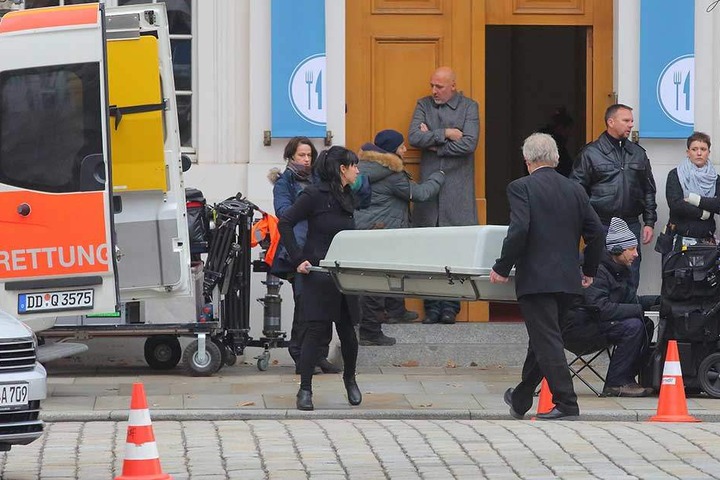 Der tote Wirt wird in einem Sarg abtransportiert.