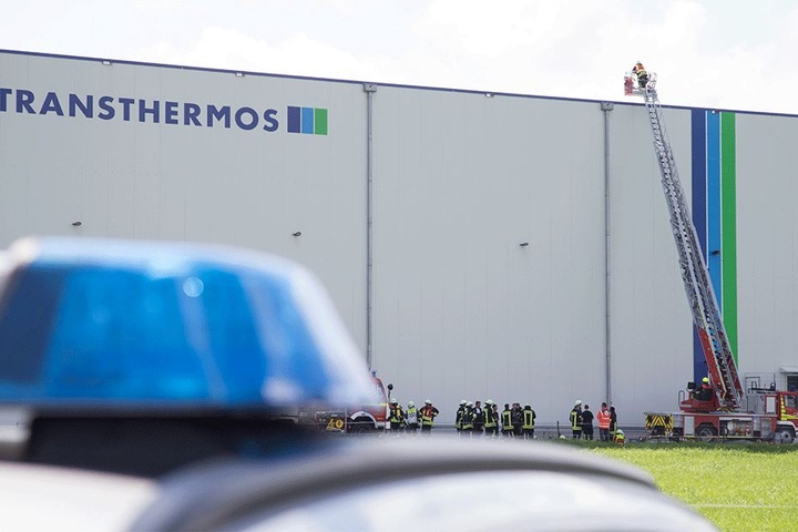 Feuerwehrleute stehen auf einer Teleskopleiter von der Lagerhalle in Dissen.