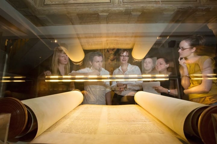 Studenten der Freien Universität Berlin betrachten am 22.06.2012 in der Alten Synagoge Erfurt das Faksimile einer Thorarolle aus dem 13. Jahrhundert.