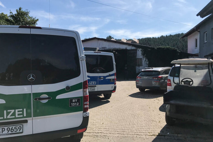 Polizeifahrzeuge stehen neben anderen Fahrzeugen auf einem Hof vor einem Stall im Allgäu. Bayerns Justiz treibt ihre Ermittlungen im Allgäuer Tierskandal voran.