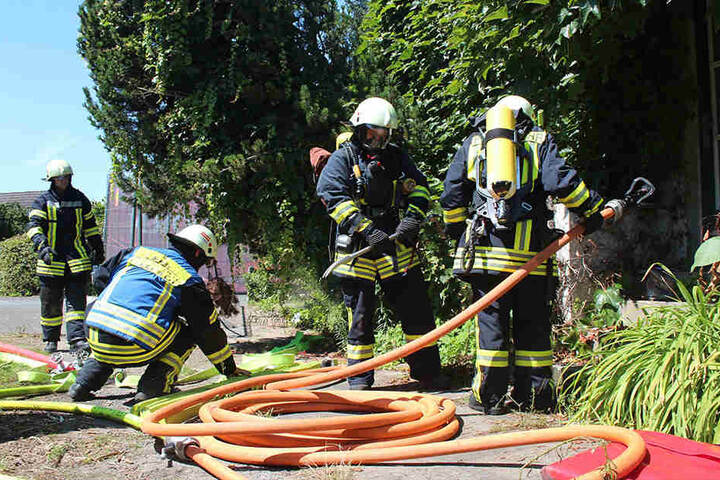 Mit Brecheisen und Wasserschlauch bewaffnet stürmt die Feuerwehr das baufällige Haus.