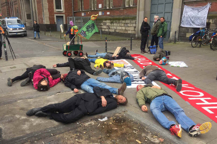 Aktivisten stellen sich vor dem Verwaltungsgericht tot. Auf dem Banner steht "Wald statt Kohle".