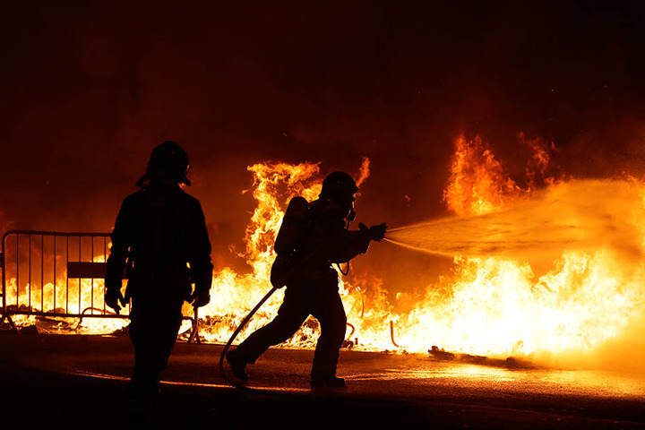 Feuerwehrleute versuchen, in Barcelona eine brennende Straßenbarrikade zu löschen.