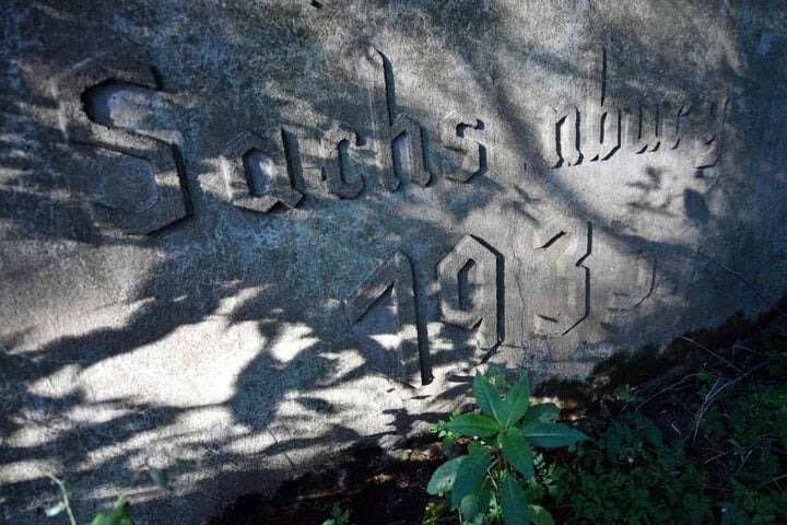 Fragmente einer Inschrift, die einst von Gefangenen des KZ Sachsenburg in Frankenberg (Sachsen), angebracht wurden.