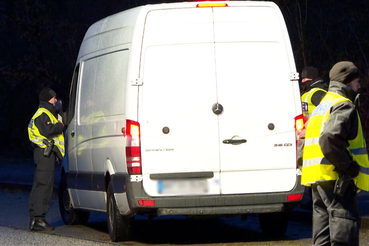 Polizeibeamte stehen an einem Transporter.