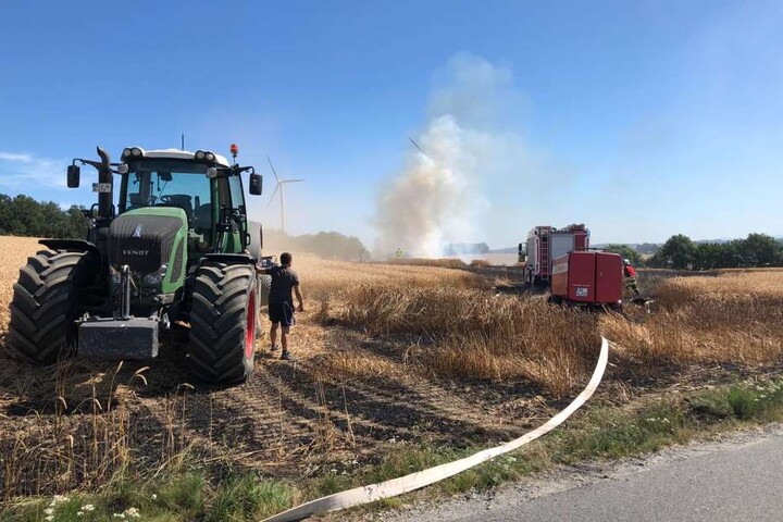 Neben der Feuerwehr ist auch der Landwirt im Einsatz, um seine Ernte zu retten.
