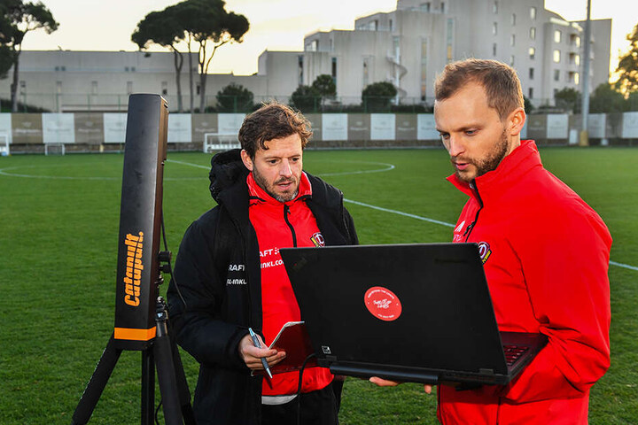 Fitnesscoach Philippe Hasler (l.) und Sportwissenschaftler Jacob Wolf überwachen die eingehenden Daten der einzelnen Dynamo-Spieler, beginnen noch auf dem Platz mit der Auswertung.