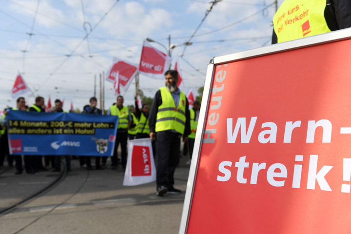Streikende stehen vor dem Betriebshof in der Einsteinstraße in München und halten Transparente und Fahnen.
