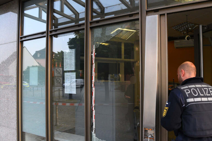 Ein Polizist geht in die Bank mit dem gesprengten Geldautomat hinein.