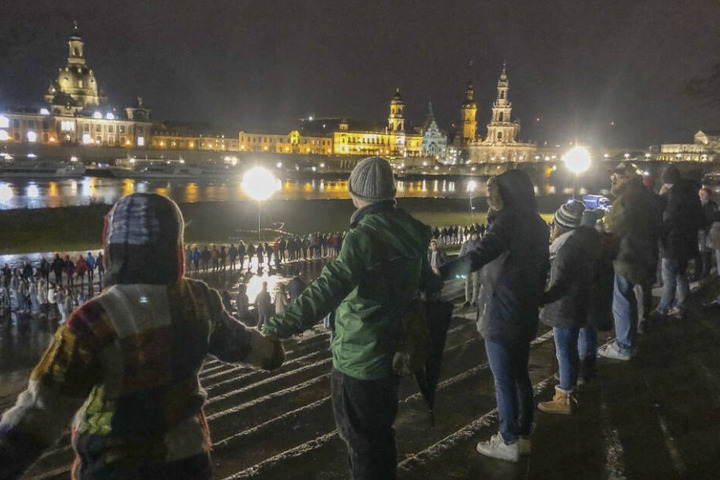 Bürger bilden am Abend vor der historischen Altstadtkulisse eine Menschenkette.