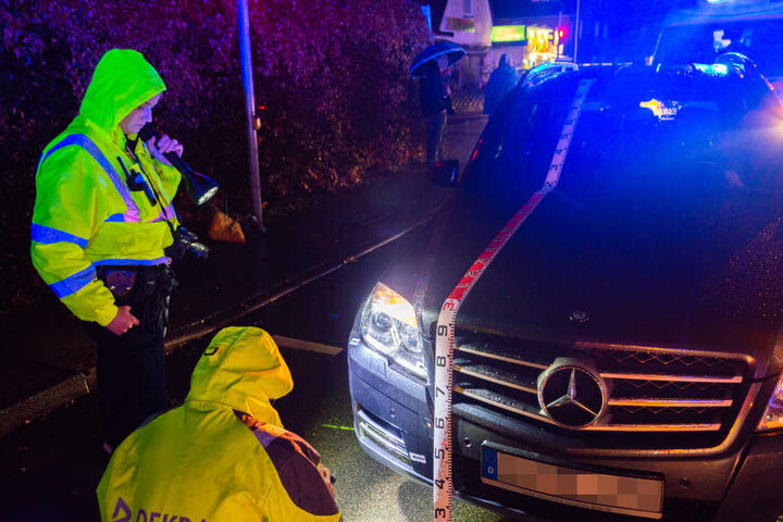 Polizisten schauen sich das Unfallauto genauer an.