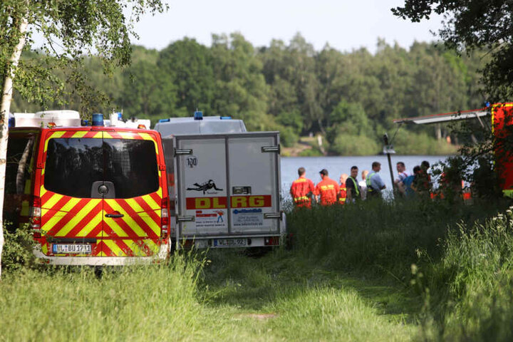Zahlreiche Einsatzkräfte von Feuerwehr und DLRG suchen am und im See nach dem Schwimmer.