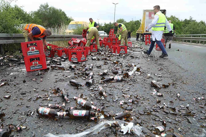 Mehrere Helfer befreien die Straße von dem Bier.