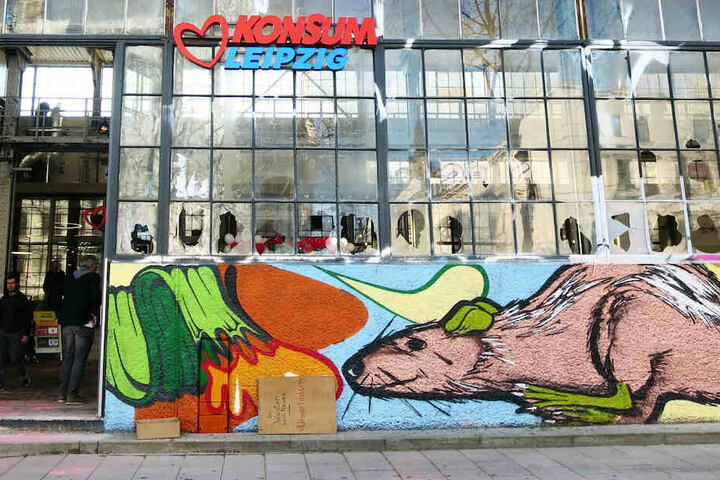 Die Glasfassade des Westwerks ziert jetzt Konsum-Werbung. Die Graffito-Ratte scheint interessiert.
