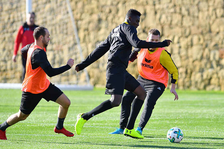 Peniel Mlapa (M.) im Training am Ball vor Manuel Konrad (r.) und Rico Benatelli.