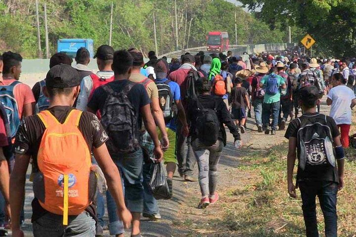 Migranten laufen eine Straße entlang.