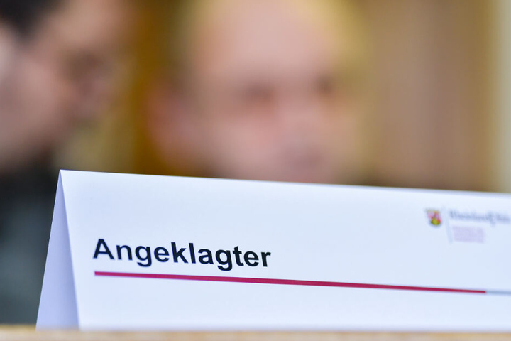 Der Angeklagte und dessen Dolmetscher unterhalten sich im Gerichtssaal des Landgerichts vor Prozessbeginn hinter einem Schild.