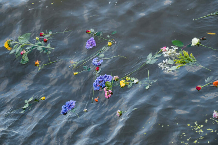 Bei einer Demonstration für Seenotrettung warfen Menschen Blumen ins Wasser.