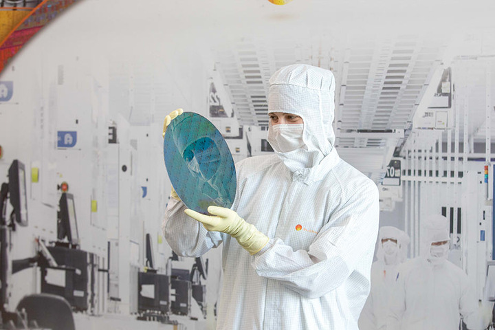 Mikrotechnologin-Azubi Lisa Marie Eisner zeigt einen Testwafer. 3500 Menschen arbeiten hier.