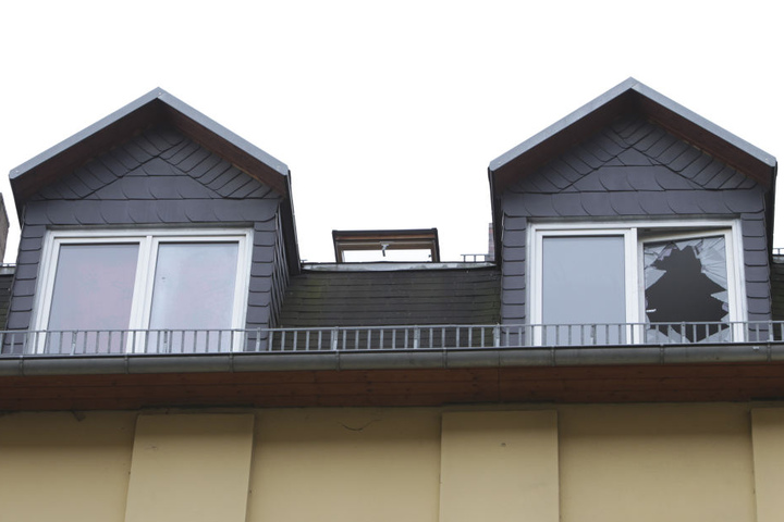 Eingeschlagenes Fenster im Dachgeschoss des Brandhauses: Die Feuerwehr musste 17 Bewohner mit einer Drehleiter retten.