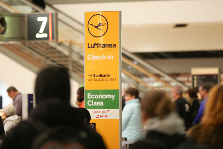 Flüggäste stehen neben einer Check-in-Säule der Lufthansa.