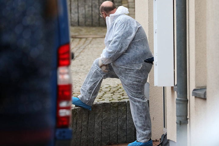 Ein Polizist in einem Overall steht vor dem Haus, in dem sich eine Anwaltskanzlei befindet, in der eine Frau erschossen wurde.