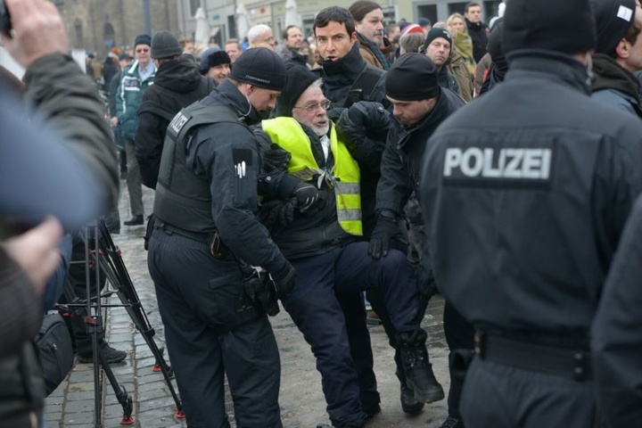 Ein Mann wird von der Polizei weggebracht.