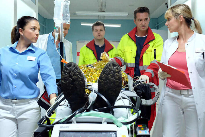 Der Notarzt (Markus Neumann, 2. v. r.) bringt ein Unfallopfer in die Sachsenklinik, das schwerste Brandverletzungen hat. Dr. Lea Peters, Dr. Kai Hoffmann (Julian Weigend, 2. v. l.) und Oberschwester Arzu müssen schnellstens reagieren. Der Patient schwebt