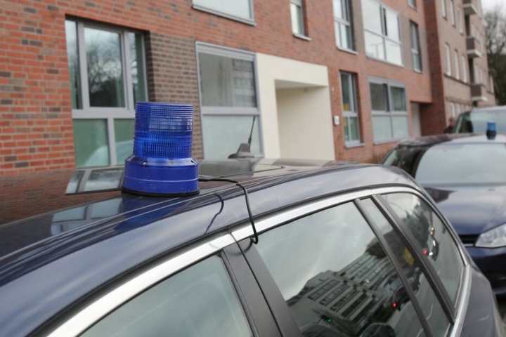 Polizeifahrzeuge stehen während einer Durchsuchung vor einem Mehrfamilienhaus in Hamburg.