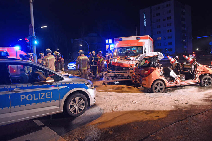 Feuerwehrleute stehen neben einem Pkw, der zuvor mit einem Rettungswagen und Polizeiauto zusammengestoßen war.