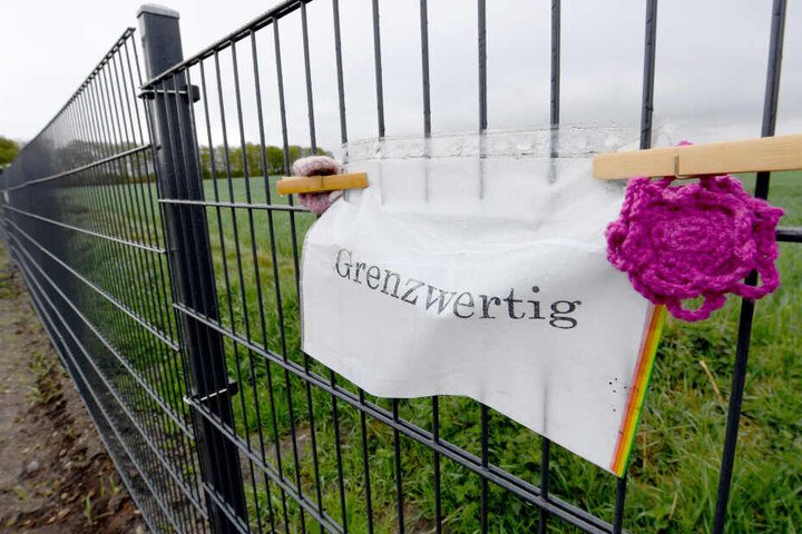 Ein Zettel mit der Aufschrift "Grenzwertig" hängt am Wildschweinzaun an der deutsch-dänischen Grenze.