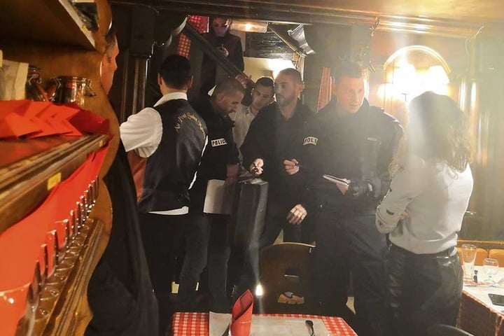 Polizisten unterhalten sich in einem dem Tatort nahe gelegenen Restaurant mit Augenzeugen.