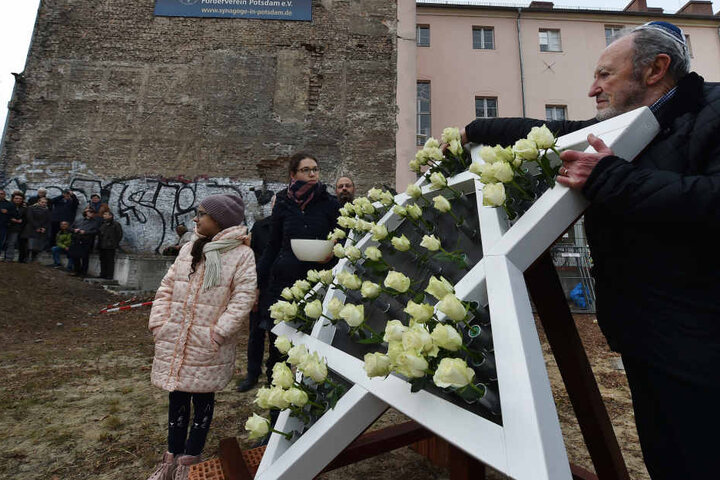 Bei einem Gedenken an die Opfer der Pogromnacht auf der Baustelle der zukünftigen Synagoge schmücken Rosen einen Davidstern.