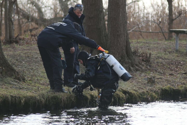 Ein Polizeitaucher kommt aus dem Wasser.