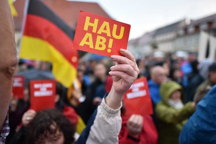 Eine Demonstrantin zeigt bei Merkels Auftritt in in Finsterwalde eine "Hau ab"-Karte.