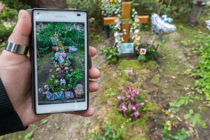 Antje Emmerlich zeigt ein Handybild, auf dem das Grab mit Blumenschmuck zu sehen ist.