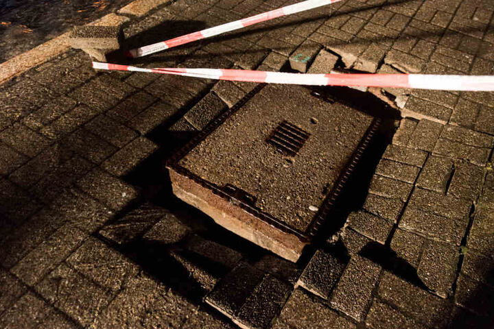 Ein aus dem Gehweg gerissener Kanaldeckel liegt in St. Blasien im Schwarzwald neben Pflasterseinen.