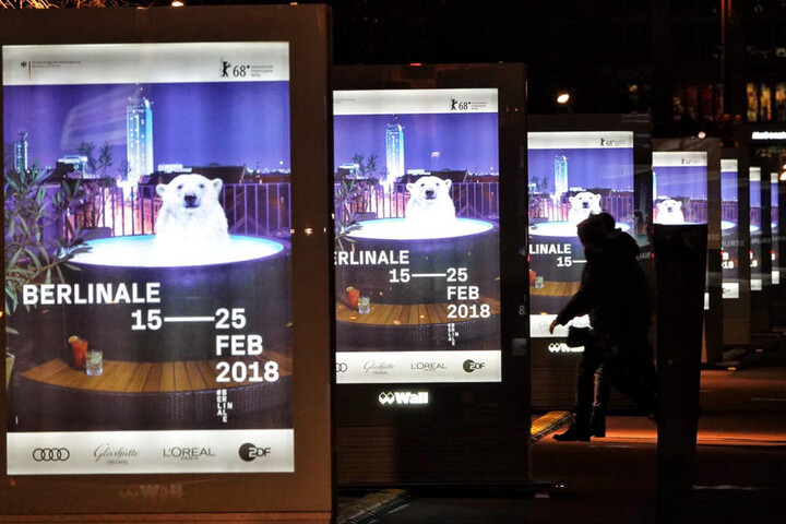 Passanten betrachten die Leuchtreklame für die Berlinale.