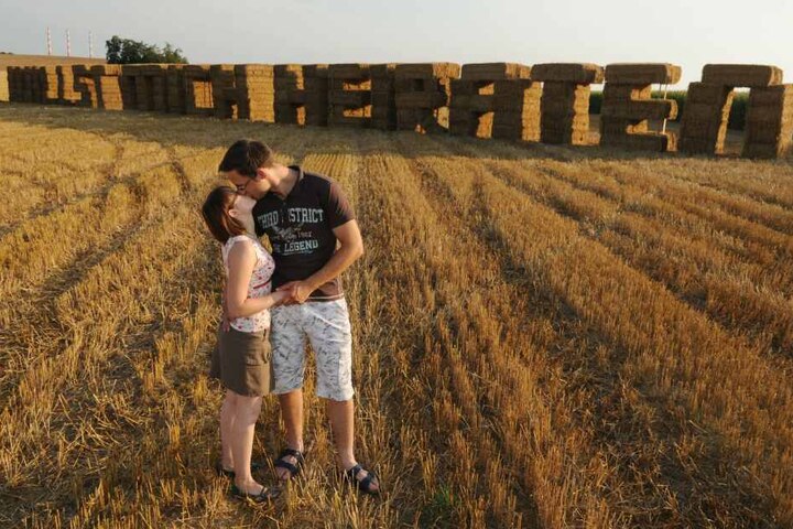 Markus Schmidt küsst am Freitag (22.08.2009) in Pettling (Oberbayern) auf Strohballen seine Verlobte Corinna Pesl vor den aus Strohballen errichteten Worten "Willst mich heiraten".