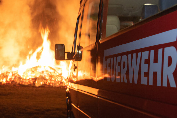 Ein Feuerwehrauto steht vor dem brennenden Osterfeuer.