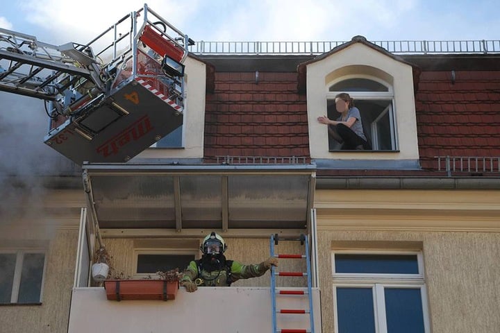 Eine junge Frau klettert aus dem Fenster.